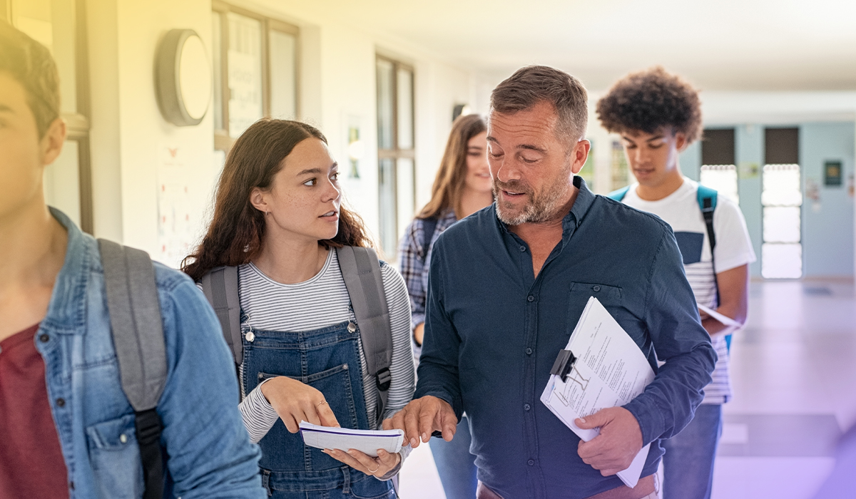 a male teacher in the hallway with his students